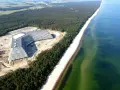 Nowy hotel Gołębiewski w budowie, majestatycznie wznoszący się nad piaszczystą plażą i lasem sosnowym, tuż przy turkusowym morzu.