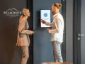 Elegancka para dyskutuje przy hotelowym ekranie. Ona w beżowym garniturze, on w białej koszuli. Idealny strój na śniadanie w hotelu.