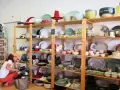 Kobieta wybiera ceramiczne naczynia, idealne pamiątki, które warto co przywieźć z Portugalii. Kolorowe talerze, miski i filiżanki na drewnianych półkach.