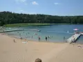 Słoneczny dzień nad jeziorem płotki. Ludzie kąpią się, pływają na dmuchanych zabawkach i odpoczywają na piaszczystej plaży.