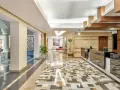 Eleganckie lobby hotelu Radisson z recepcją, ozdobnymi kolumnami i mozaikową podłogą. Radisson individuals witają tu gości.