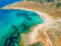Widok z lotu ptaka na turkusowe morze i piaszczyste bari plaże z rzędami parasoli.
