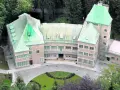 Zameczek w Wiśle, otoczony lasem, oferuje noclegi w malowniczym otoczeniu. Zielone dachy i kamienna fasada tworzą urokliwy widok.