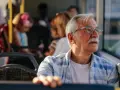 Starszy pan w okularach, podróżujący autobusem w Szczecinie, zastanawia się, czy 70 latek płaci za komunikację miejską.