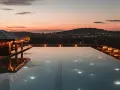 Zachód słońca nad miastem, basen na dachu hotelu w Polsce, oświetlony girlandami i lampkami.