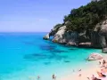 Cala Goloritze: turkusowa woda, skaliste klify i plażowicze cieszący się słońcem.