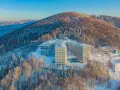 Nowoczesny hotel Crystal w zimowej scenerii, otoczony ośnieżonym lasem. To idealne miejsce na wypoczynek w Wiśle, górskim kurorcie.