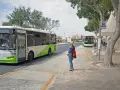 Kobieta czeka na autobus na Malcie. W tle widać autobusy, w tym jeden jadący w kierunku lotniska.