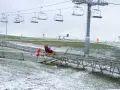 Dwie osoby zjeżdżają na sankach po torze saneczkowym w Mikołajkach. W tle widać wyciąg krzesełkowy i ośnieżone wzgórza.