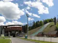 Skocznia narciarska Malinka im. Adama Małysza w Wiśle z trybunami i zielonym zeskokiem.