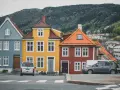Kolorowe domy w Norwegii, jak te niebieski, żółty i czerwony, to jedna z wielu ciekawostek o Norwegii. W tle widać wzgórza i zabudowania.
