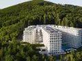 Nowy hotel w Wiśle, Crystal Mountain, wtopiony w zielone zbocze góry. Nowoczesna architektura z licznymi balkonami i basenem.