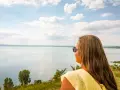 Kobieta w żółtej bluzce podziwia rozległe jezioro Balaton.