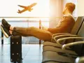 Mężczyzna z nogami na walizce czeka na lotnisku. Samolot startuje. Czyżby czekał na niego, czy to tylko efekt **overbooking**?