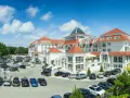 Elegancki hotel 5 gwiazdkowy nad morzem z przestronnym parkingiem pełnym samochodów.