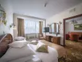 Przytulny pokój hotelowy w Białymstoku z wygodnym łóżkiem, toaletką i widokiem na salon.