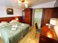 Przytulny pokój hotelowy z dużym łóżkiem, szafą i biurkiem. Czy żeby wynająć pokój w hotelu trzeba mieć 18 lat?