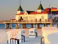 Plaża z koszami i molo, gdzie widać budynek restauracji i niemiecką flagę. Atrakcje po niemieckiej stronie Świnoujścia zachęcają do spacerów.