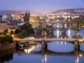 Praga nocą, z wieloma mostami na Wełtawie i oświetlonymi budynkami. Ciekawe ciekawostki o Czechach czekają na odkrycie w tym magicznym mieście.