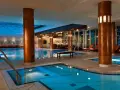 Basen hotelowy Radisson Blu Radebeul z niebieską wodą, drewnianymi kolumnami i leżakami.