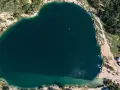 Serce polskiego balatonu, turkusowa woda, otoczona zielenią i piaszczystymi plażami. W oddali widać małą łódkę.