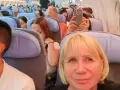 W samolocie, przygotowując się na najdłuższy lot samolotem, pasażerowie siedzą w rzędach. Kobieta robi zdjęcie telefonem.
