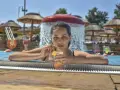 Kobieta w basenie z drinkiem, relaksująca się w słońcu. Idealny dzień all inclusive soft.
