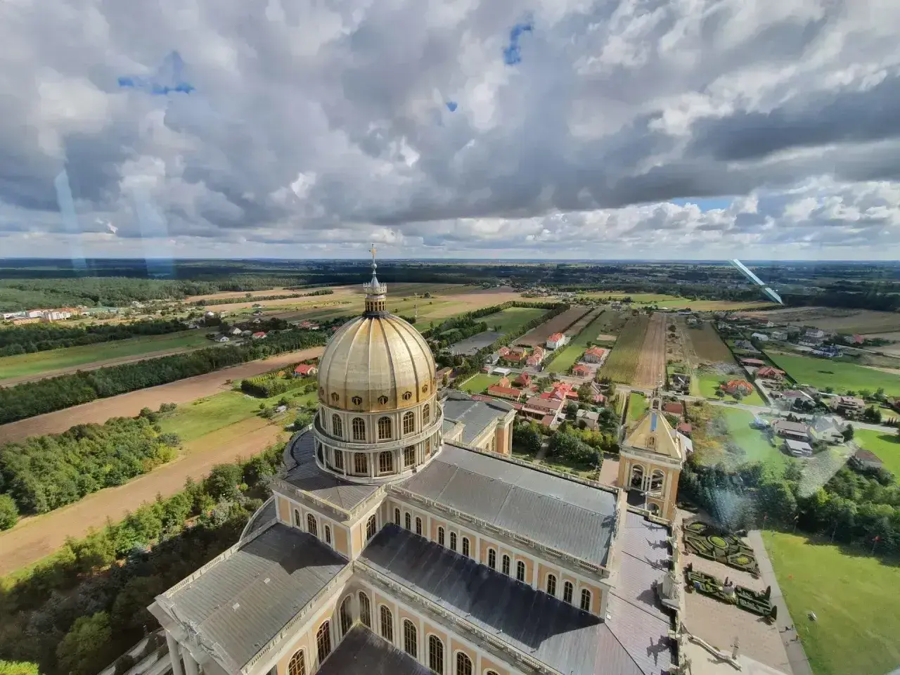 Bazylika w Licheniu z lotu ptaka. Widok na złotą kopułę i okoliczne pola. Sprawdź licheń cennik atrakcji.