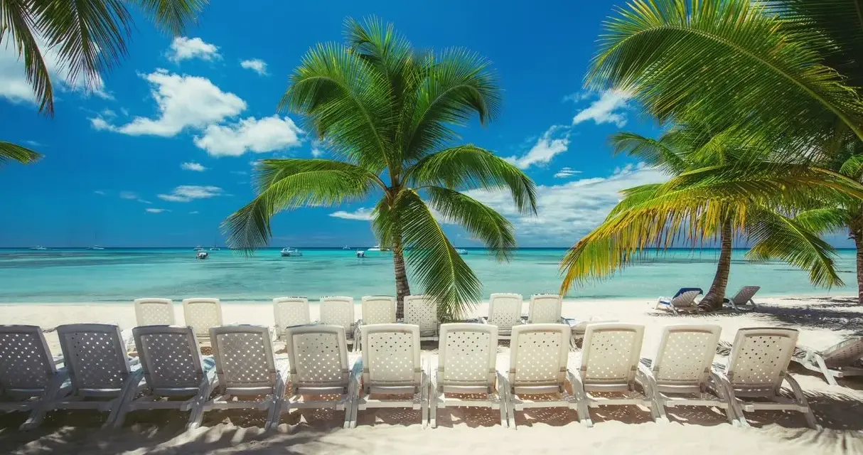 Rajska plaża z palmami i leżakami. Zastanawiasz się, ile się leci na Dominikanę, by poczuć ten spokój?