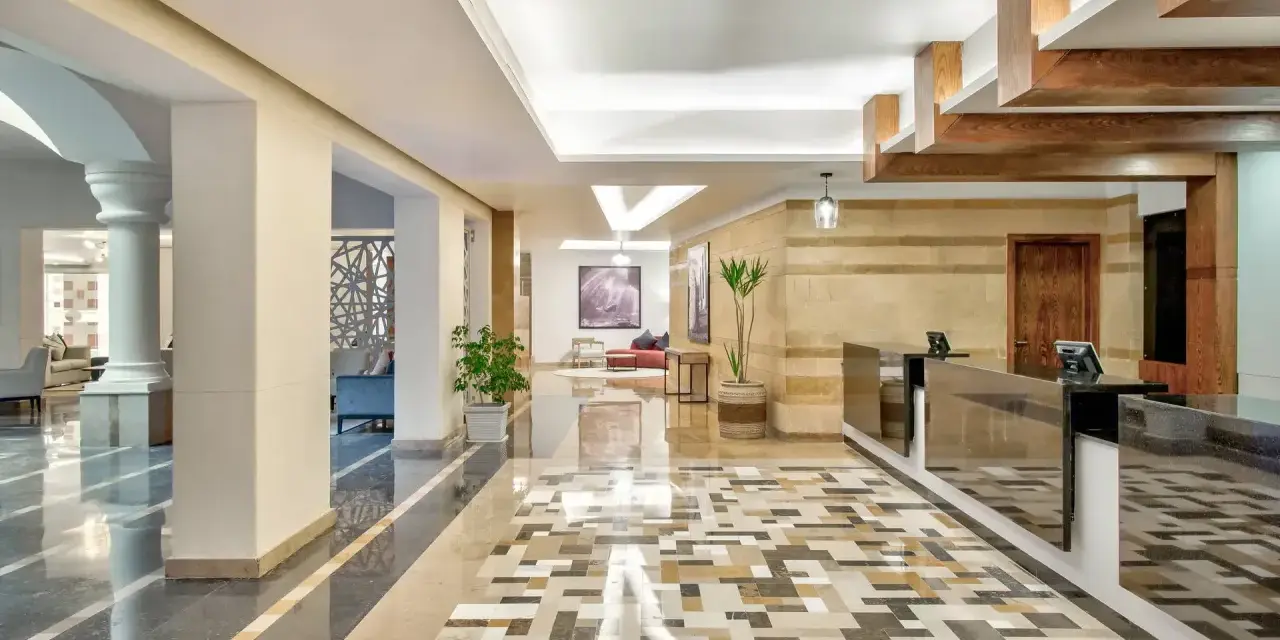 Eleganckie lobby hotelu Radisson z recepcją, ozdobnymi kolumnami i mozaikową podłogą. Radisson individuals witają tu gości.