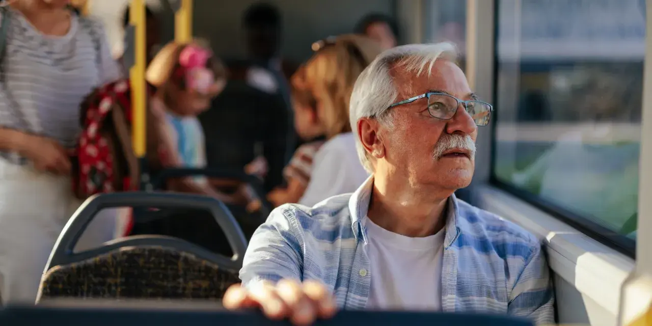 Starszy pan w okularach, podróżujący autobusem w Szczecinie, zastanawia się, czy 70 latek płaci za komunikację miejską.