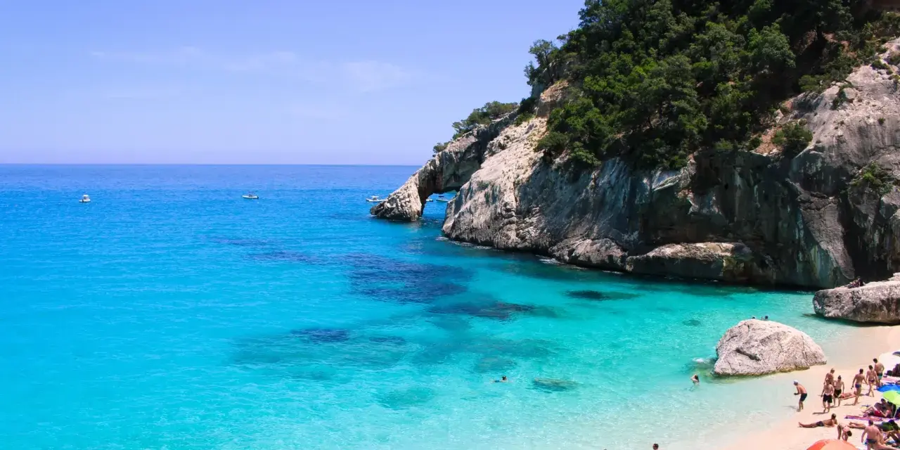 Cala Goloritze: turkusowa woda, skaliste klify i plażowicze cieszący się słońcem.