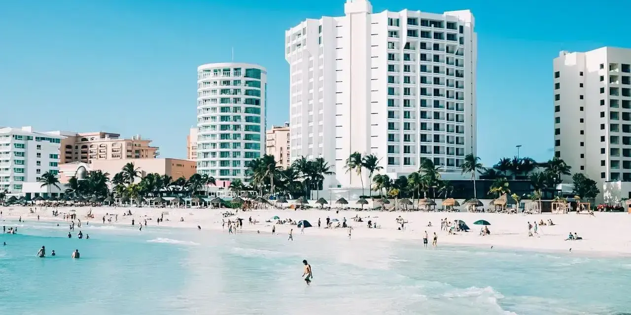 Piękna plaża z turkusową wodą i hotelami w tle. Zastanawiasz się, ile się leci do Meksyku, by tu dotrzeć?