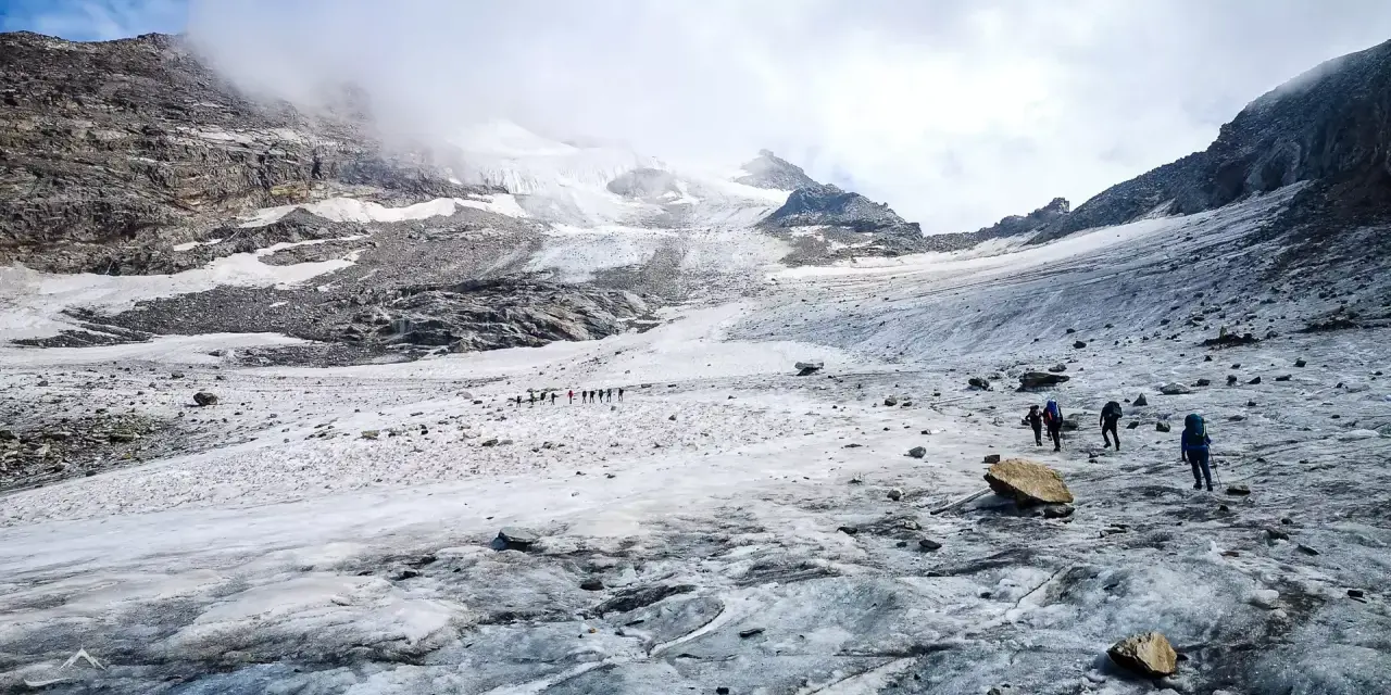 Grupa turystów wędruje po lodowcu w kierunku majestatycznego masywu Monte Rosa.