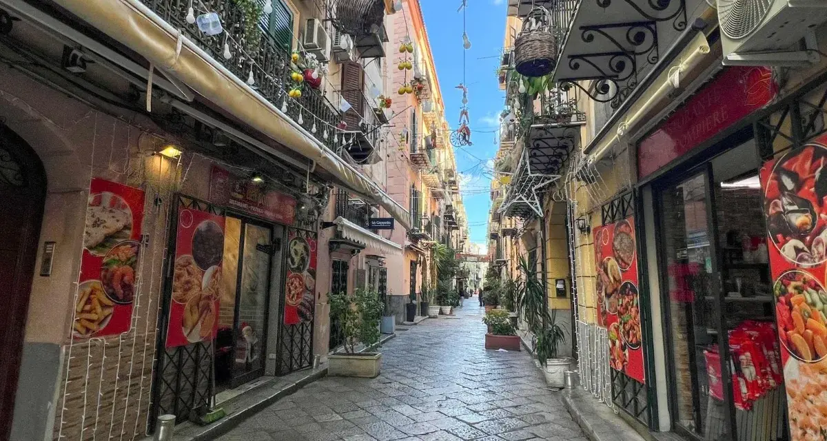 Wąska uliczka w Palermo, stolicy Sycylii, z restauracjami i balkonami ozdobionymi lampkami.