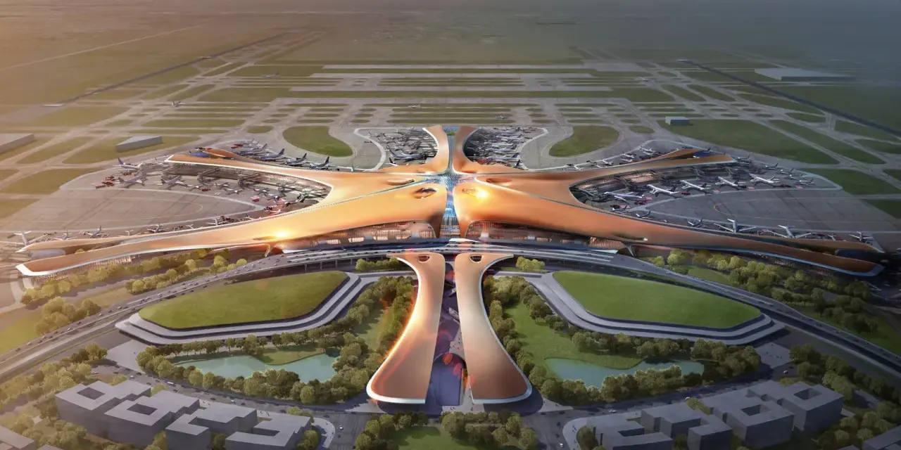 Futurystyczny terminal lotniska, przypominający rozgwiazdę, z samolotami na płycie. To największe lotnisko na świecie, z nowoczesną architekturą i otaczającą zielenią.