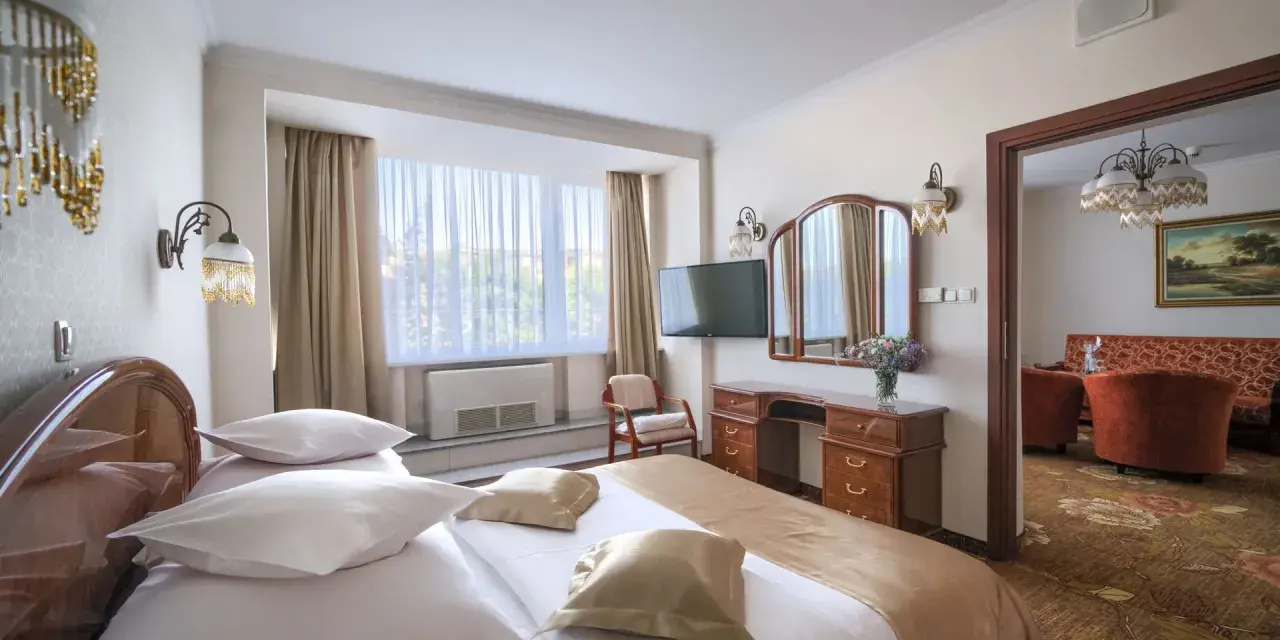 Przytulny pokój hotelowy w Białymstoku z wygodnym łóżkiem, toaletką i widokiem na salon.