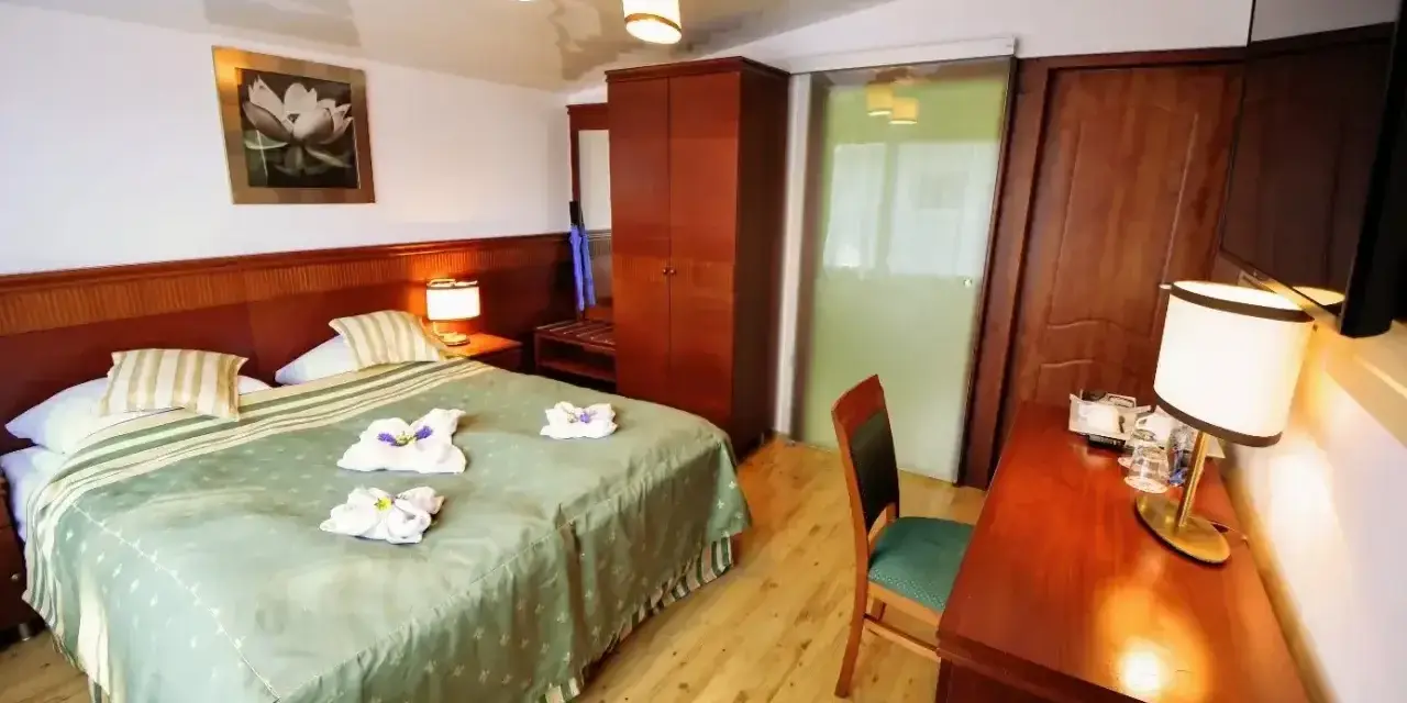 Przytulny pokój hotelowy z dużym łóżkiem, szafą i biurkiem. Czy żeby wynająć pokój w hotelu trzeba mieć 18 lat?