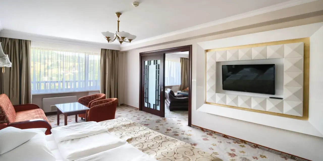Wnętrze pokoju hotelowego z łóżkiem, kanapą i fotelem. Warto sprawdzić, ile pokoi ma Hotel Gołębiewski w Wiśle, by wybrać idealny dla siebie.