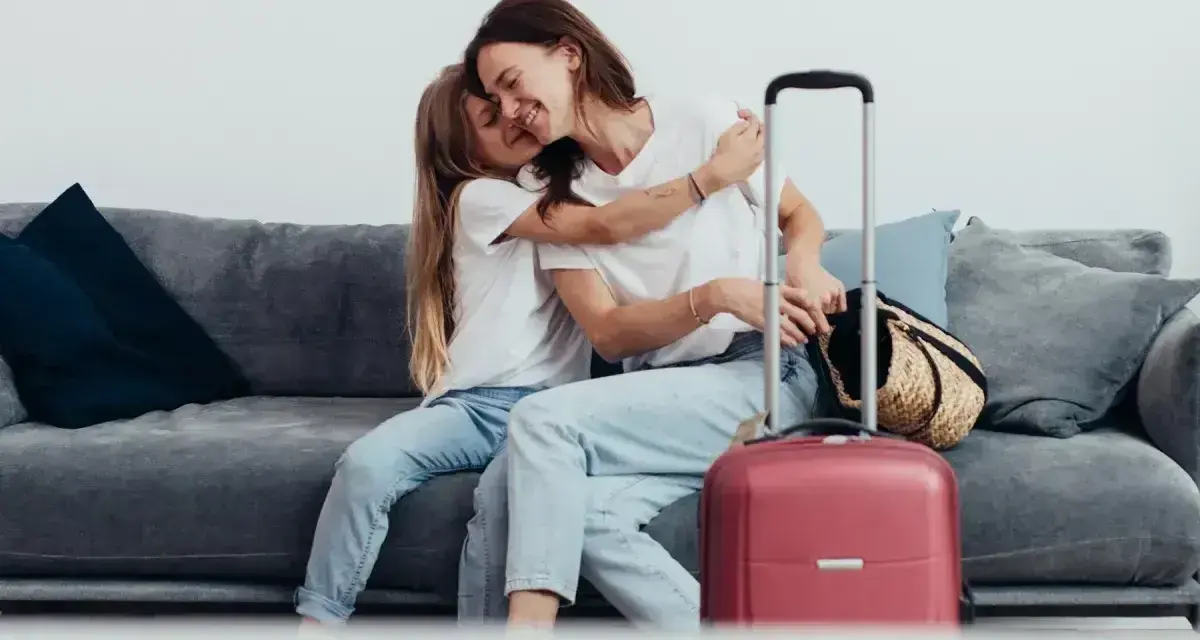 Mama i córka przytulają się na kanapie, obok walizka. Wszyscy, którzy chcą zameldować się w hotelu, mogą tu poczuć się jak w domu.