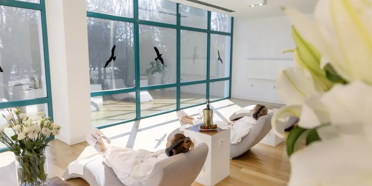 Relaks w spa, idealne ciechocinek atrakcje na weekend. Dwie kobiety w szlafrokach odpoczywają w fotelach, słuchając muzyki.