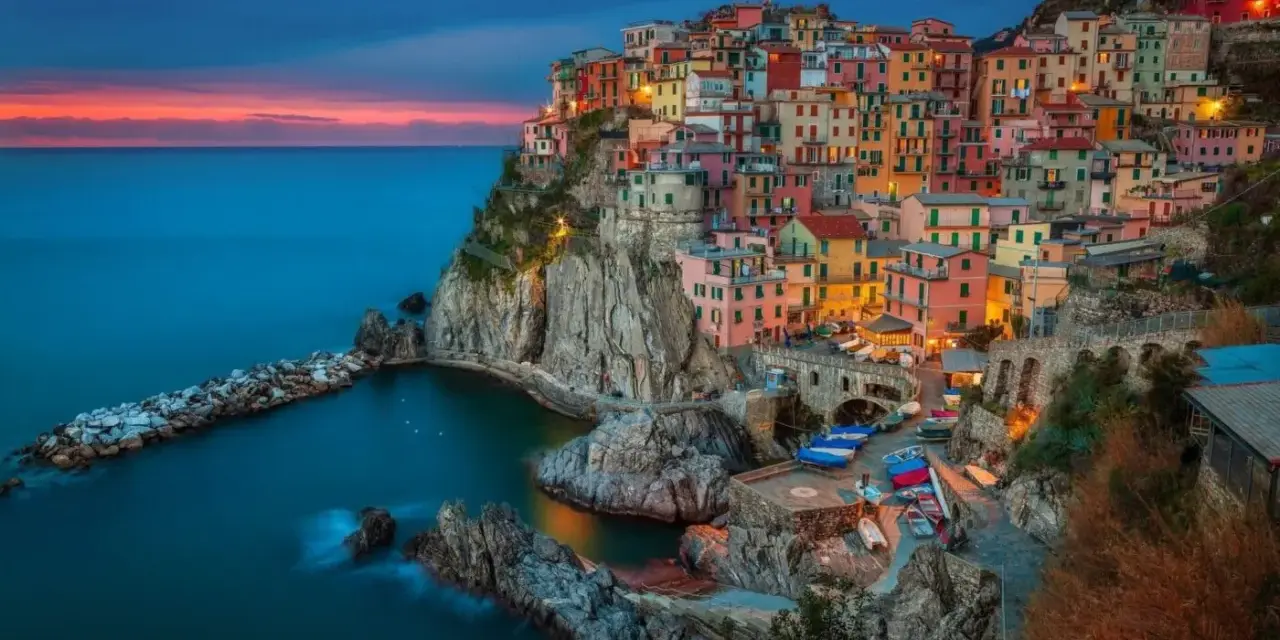 Kolorowe domy Cinque Terre, jedne z najpiękniejszych regionów Włoch, wznoszą się na klifie nad morzem o zachodzie słońca.