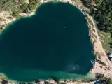 Serce polskiego balatonu, turkusowa woda, otoczona zielenią i piaszczystymi plażami. W oddali widać małą łódkę.