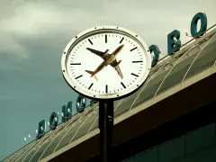 Zegar lotniskowy z samolotem zamiast wskazówki. Zastanawiasz się, ile wcześniej trzeba być na lotnisku z bagażem podręcznym?