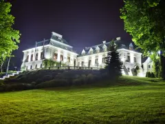 Elegancki hotel z atrakcjami dla dorosłych, nocą oświetlony, z pięknym ogrodem i zielonym trawnikiem.