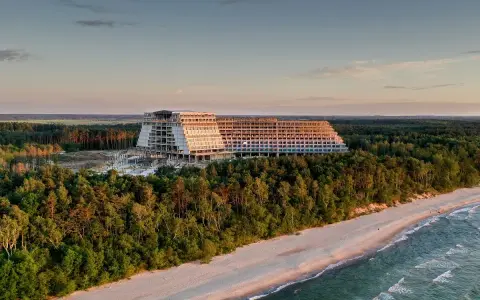 Ogromny, niedokończony hotel, który ma być największym hotelem w Polsce, góruje nad lasem i plażą o zachodzie słońca.