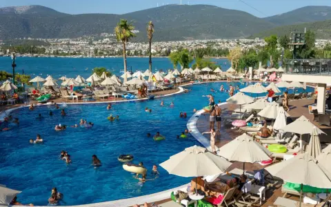 Ludzie kąpią się i relaksują przy basenie w kurorcie z widokiem na morze i góry. Idealne miejsce na wakacje ultra all inclusive.