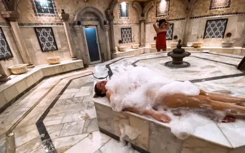 Kobieta w pianie w łaźni hammam. To tradycyjne tureckie łaźnie parowe, miejsce relaksu i oczyszczenia.
