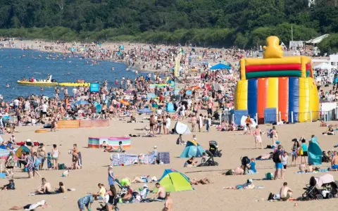 Tłum ludzi na plaży, dmuchany zamek, łodzie na wodzie – wakacje all inclusive Polska w pełni!