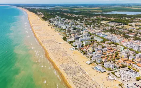 Słoneczna bibione plaża tętni życiem. Tysiące leżaków i parasoli tworzą barwny dywan na piasku, a turkusowe morze zaprasza do kąpieli.